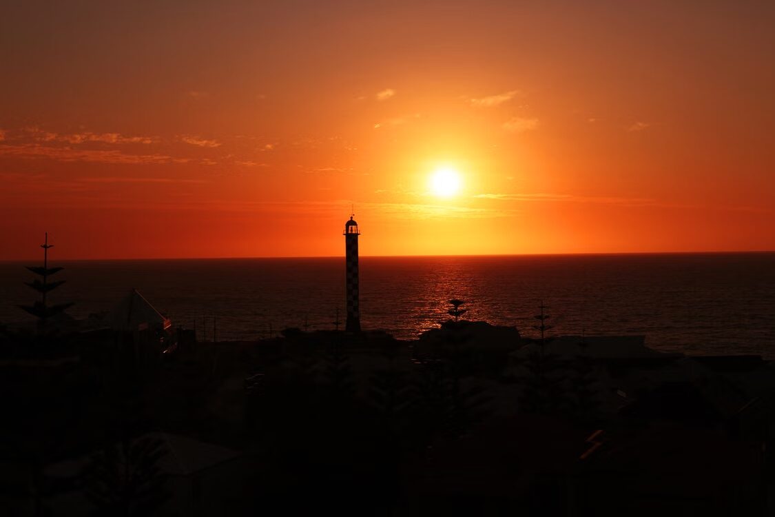 Sunset over the ocean with a lighthouse silhouette in Perth, Western Australia. Ideal for calibration services imagery.